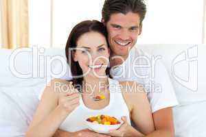 couple eating fruits lying on their bed