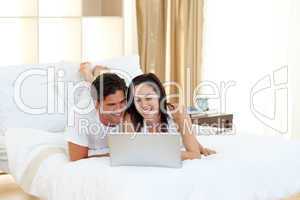 couple using a laptop on their bed