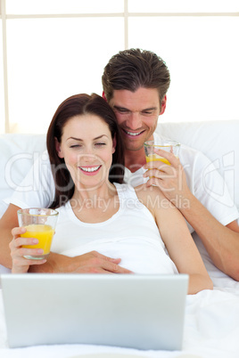 Lovers using a laptop on their bed
