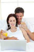 Lovers using a laptop on their bed