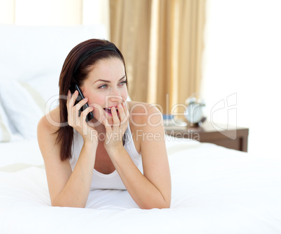 woman on phone lying on her bed