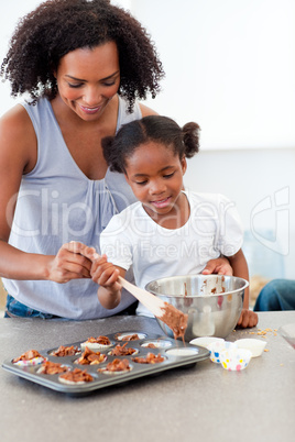 Afro-american little girl preparing biscuits with her mother