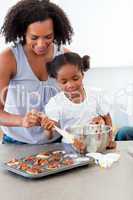 Afro-american little girl preparing biscuits with her mother