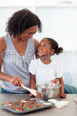 Happy mother helping her daughter cooking biscuits