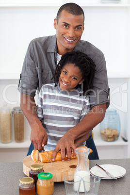 Smiling father and his son cutting bread