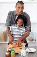 Smiling father and his son cutting bread