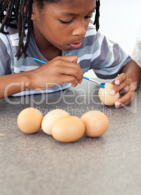 Cute Afro-american little boy painting eggs