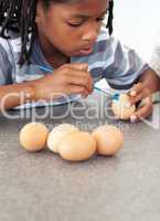 Cute Afro-american little boy painting eggs
