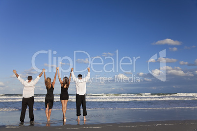 Four Young People, Two Couples, Arms Up Celebrating On Beach