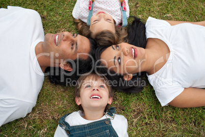 Joyful family lying in a circle on the grass