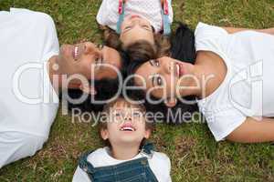 Joyful family lying in a circle on the grass