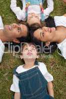 Lively family lying in a circle on the grass