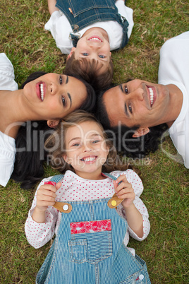 Little girl lying in a circle with her family in a park