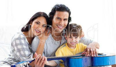 Caring parents playing guitar with their son