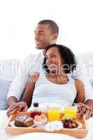 Enamoured couple having breakfast lying on their bed