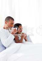 Enamoured couple drinking a coffee on their bed