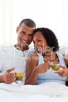 Affectionate couple drinking a cup of tea on their bed