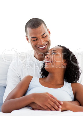 Enamoured couple cuddling lying on their bed