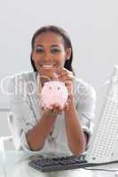 Smiling ethnic businesswoman saving money in a piggybank