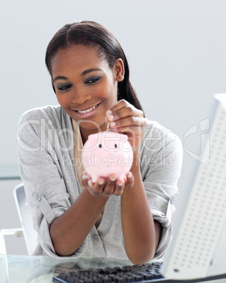 Assertive Afro-american businesswoman saving money in a piggyban