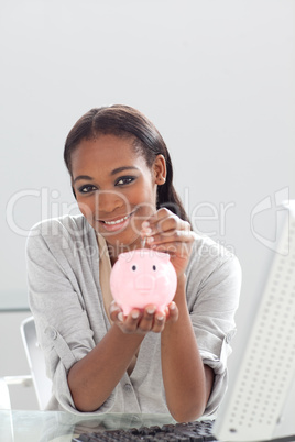 Confident ethnic businesswoman saving money in a piggybank