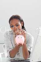 Confident ethnic businesswoman saving money in a piggybank