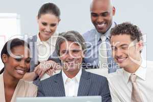 Smiling Multi-ethnic business group using a laptop