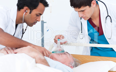 Young doctor putting oxygen mask on a senior patient