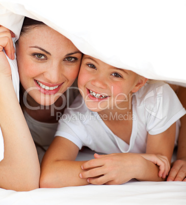 Cheerful mother and her little girl playing together on a bed