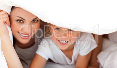 Happy mother and her blond girl playing together on a bed