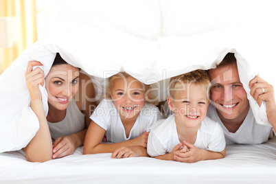 Young family playing together on a bed