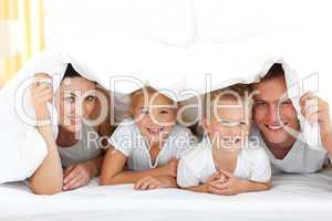 Young family playing together on a bed