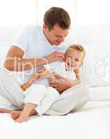 Happy father playing with his boy on a bed