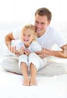 Attractive father playing with his little girl on a bed