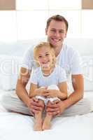 Caring father with his little girl sitting on bed