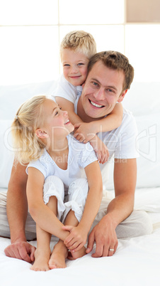 Caring father with his children sitting on bed