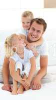 Caring father with his children sitting on bed