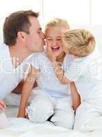 Loving family playing sitting on a bed