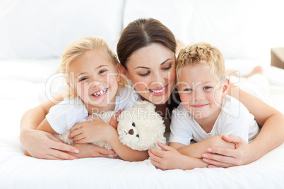 Cheerful children with their mother lying on a bed