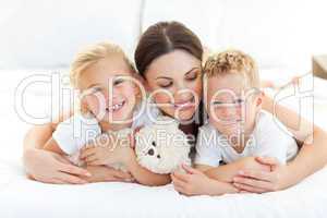 Cheerful children with their mother lying on a bed