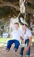 Jolly father pushing his son on a swing