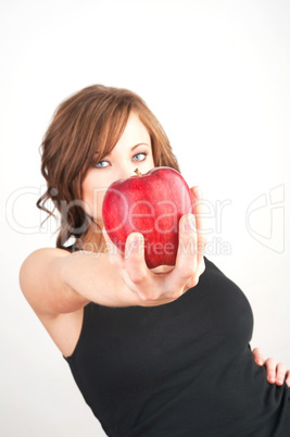 Beautiful girl holding a red apple, extended toward camera