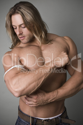 A bodybuilder measuring the increase in his bicep