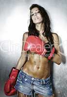 Young female boxer topless in jeans and boxing gloves