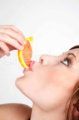 Beautiful girl biting into a slice of grapefruit