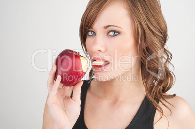 Beautiful girl biting off a piece of a red apple