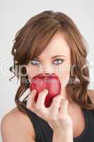 Beautiful girl holding an apple in front of her face