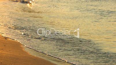 HD Gold waves on a sandy beach in sunrise, closeup