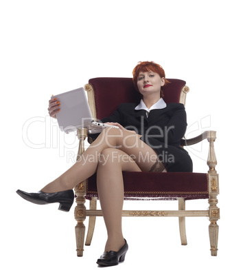 Red young woman in sexy business suit at old-fashion chair with laptop