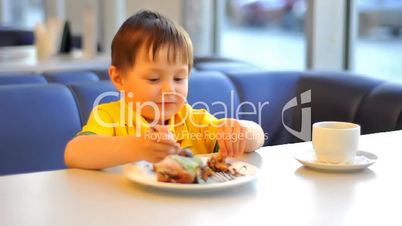 Boy eat cake in cafe